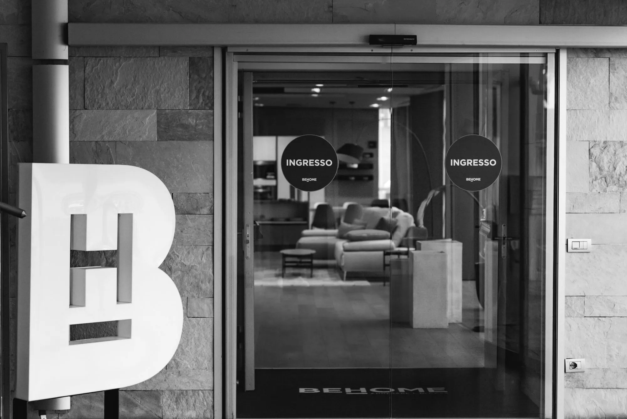 Dettaglio delle porte d'ingresso di uno showroom BEHOME che invitano il cliente a entrare, rappresentando perfettamente la visione dell'azienda: farti sentire a casa fin dal primo momento.