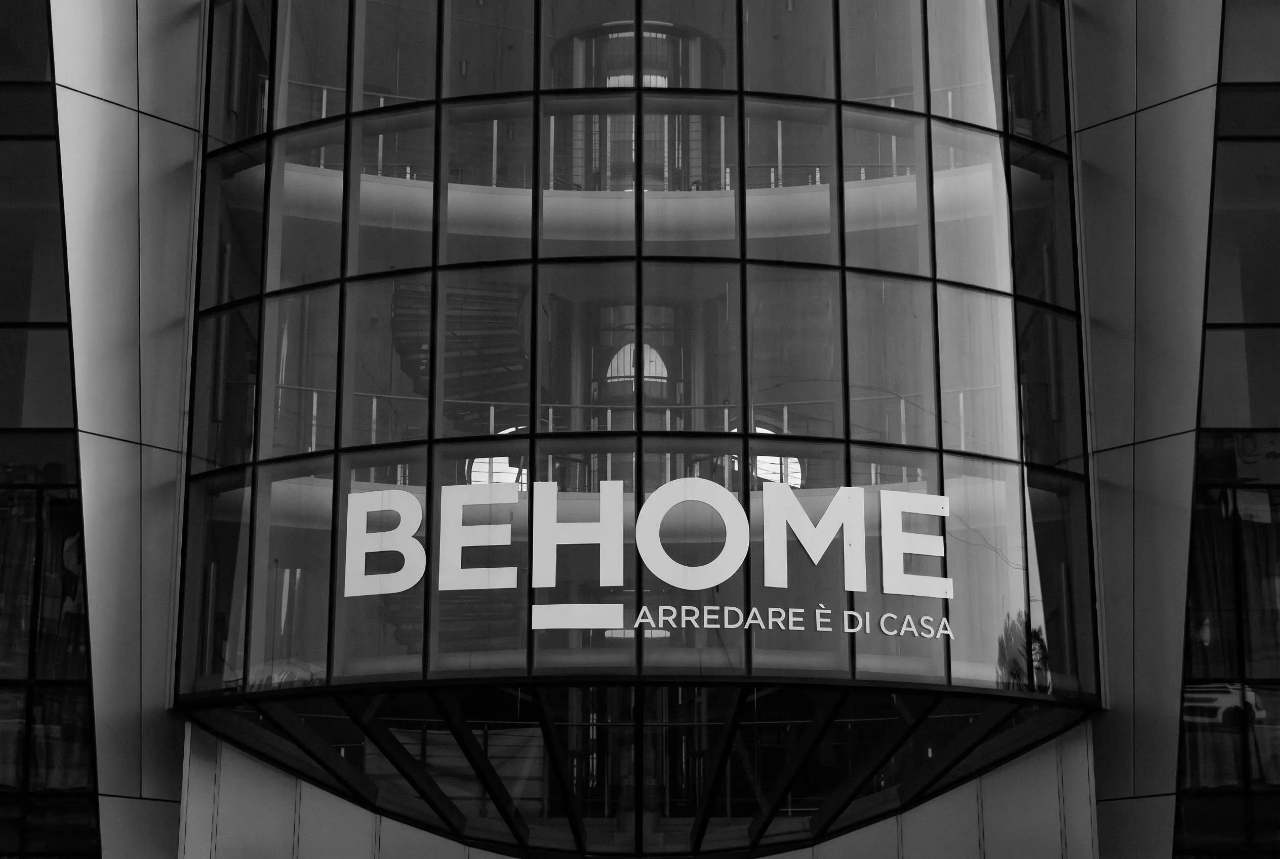 Imponente facciata a vetri dello store BEHOME, simbolo della solidità del brand e punto di riferimento per l'arredamento d'interni Made in Italy.